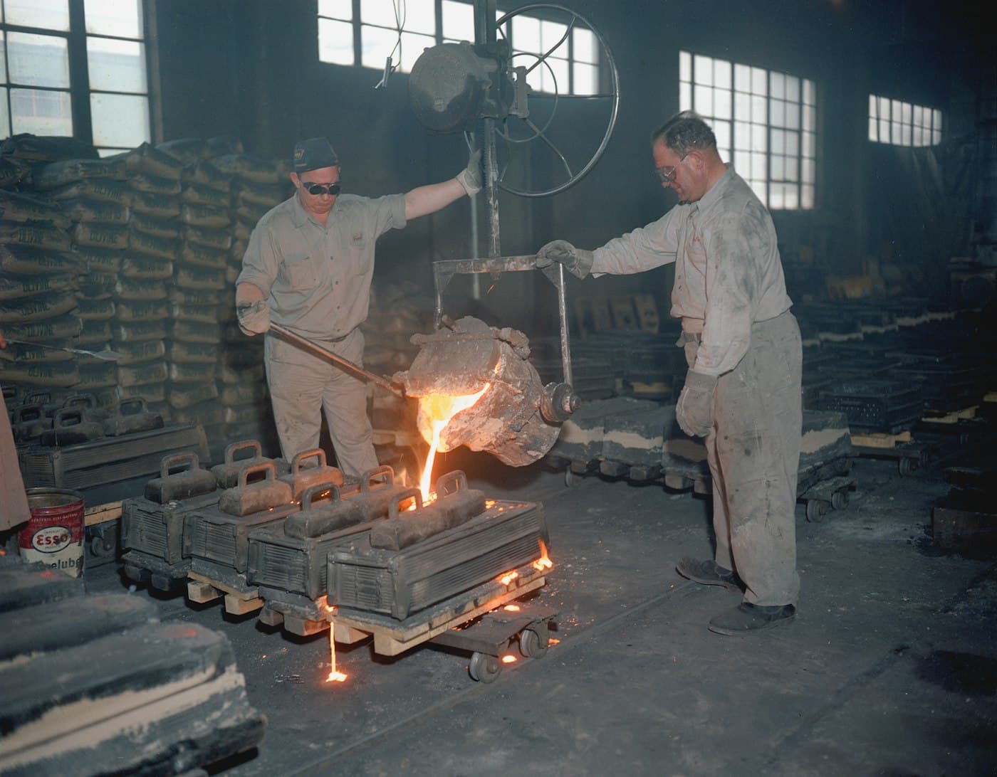 Foundry workers pouring metal into ingot moulds