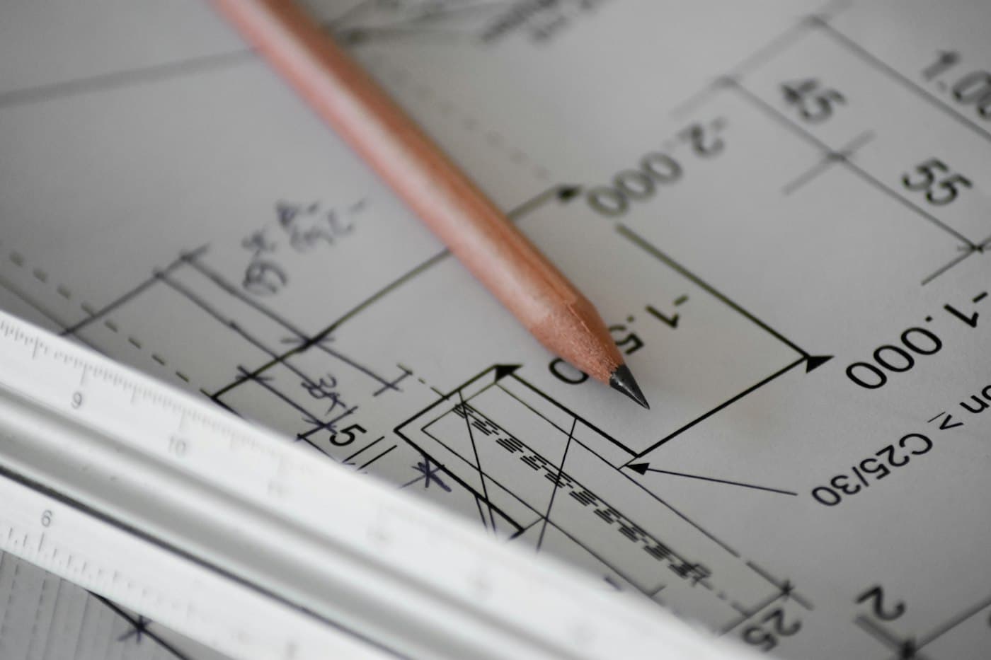 Pencil resting on a dimensioned technical drawing